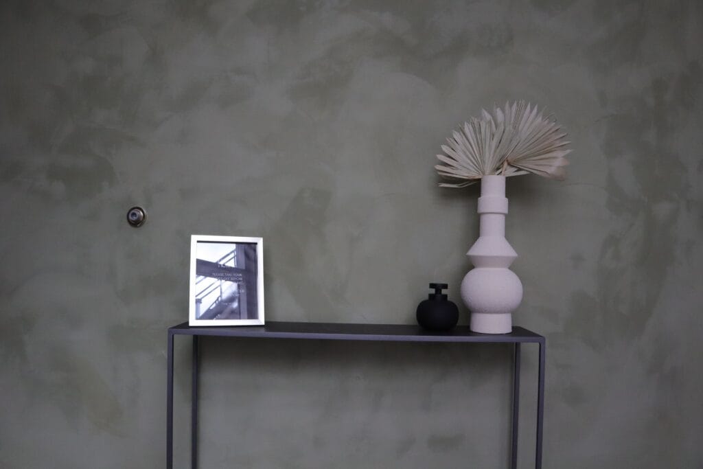 Concrete effect plaster wall behind a console and arched mirror, Toronto