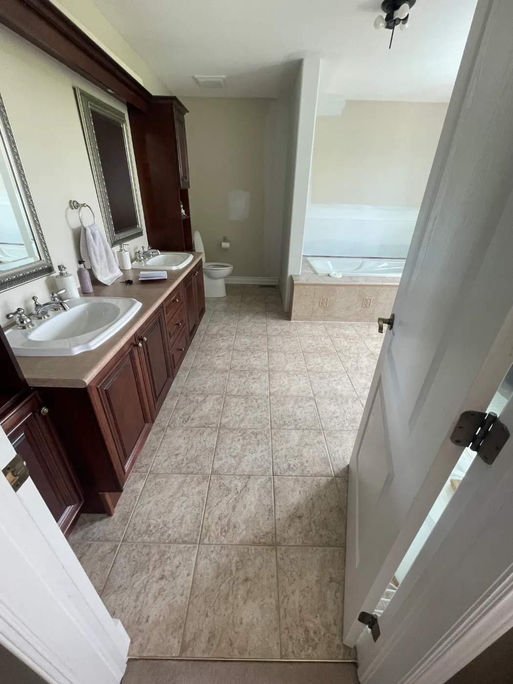 Glazed cream ceramic bathroom floor tile with grout grid before refinishing