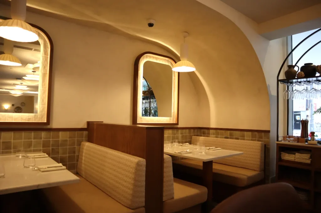 Smooth light limewash dining room with lit arched mirrors and pendants