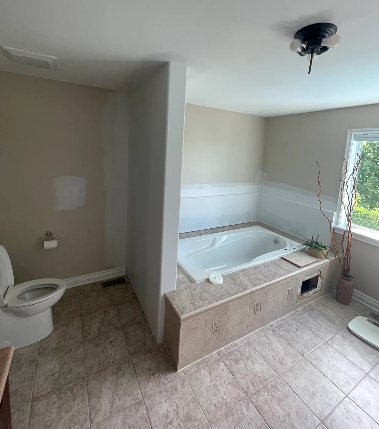 Tiled soaker tub platform with bullnose edge and relief accent tiles before microcement